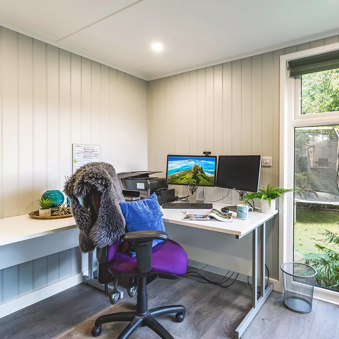 Inside view of redwood garden office with desk chair and desk and PC and indoor plants 