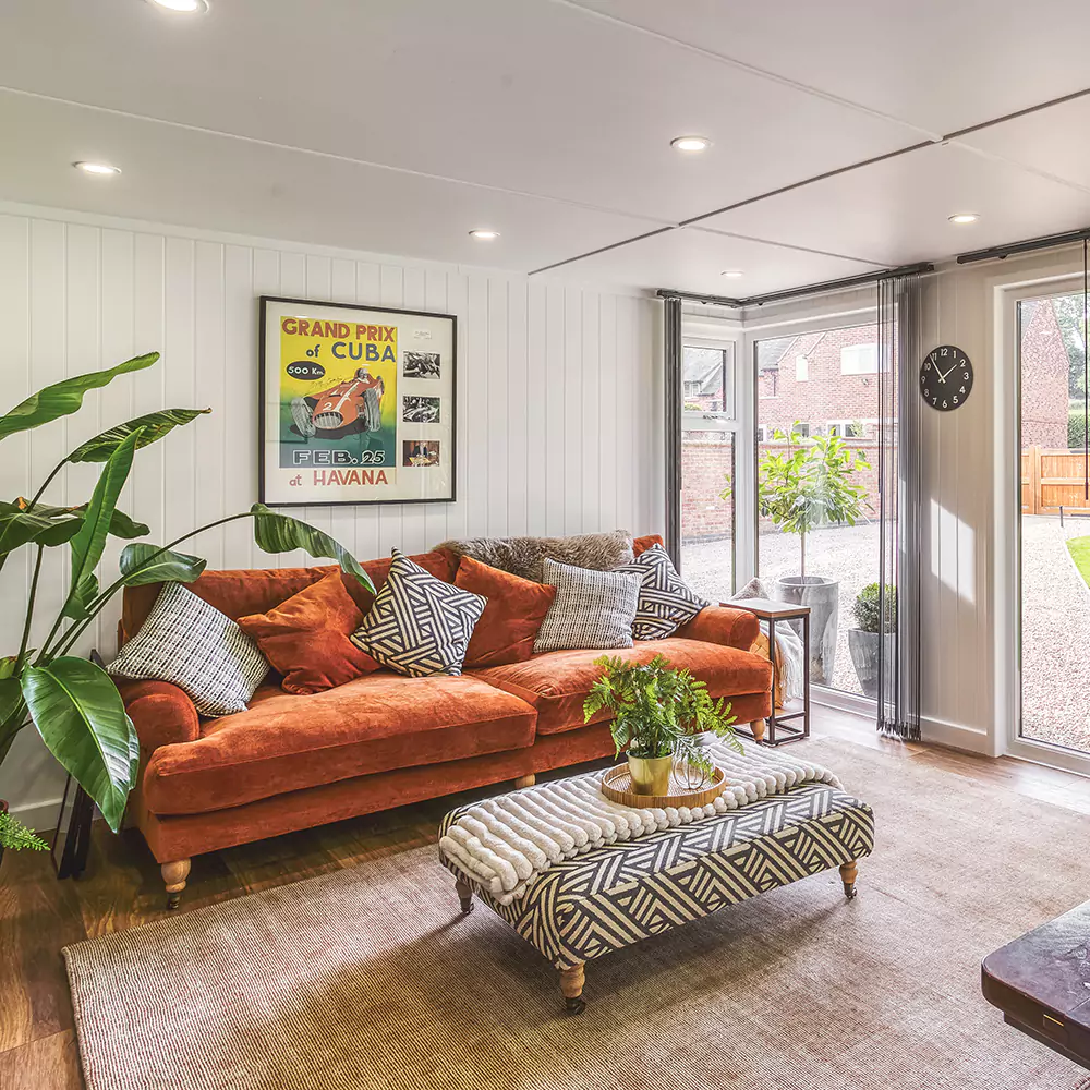 Interior of a small garden room with rust sofa & soft furnishings