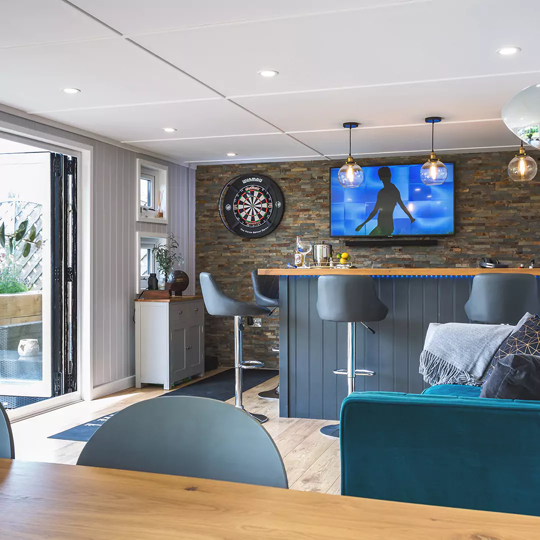 Internal of Garden Bar with slate feature wall and grey bar stools and dart board and television with chandeliers