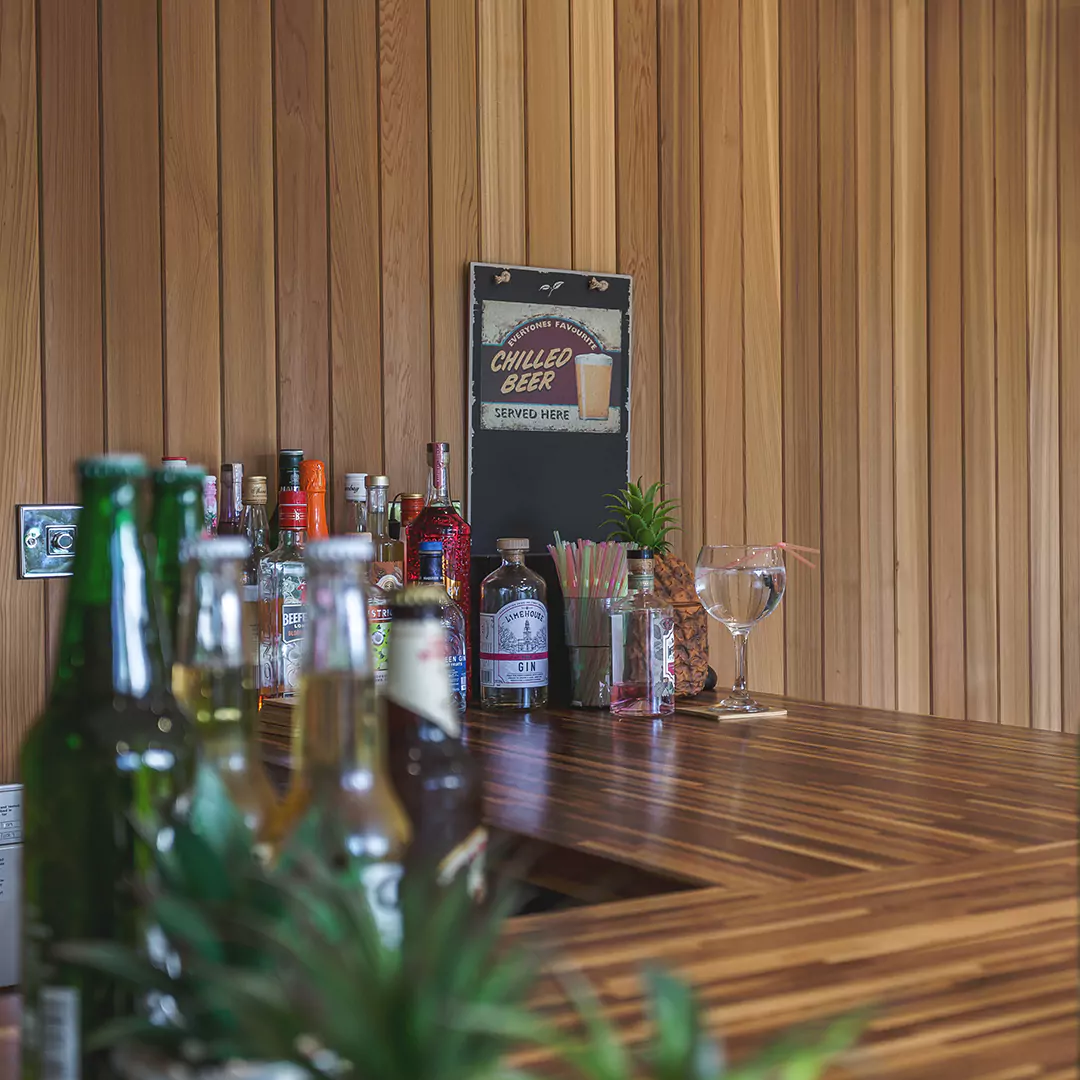 inside view of garden bar with bifolds and a wooden table topped with lots of bottles of beer
