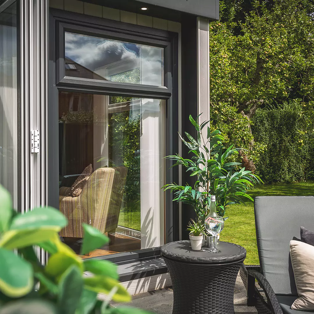 a patio area in front of garden bar with bifolds with a table and chairs and a potted plant