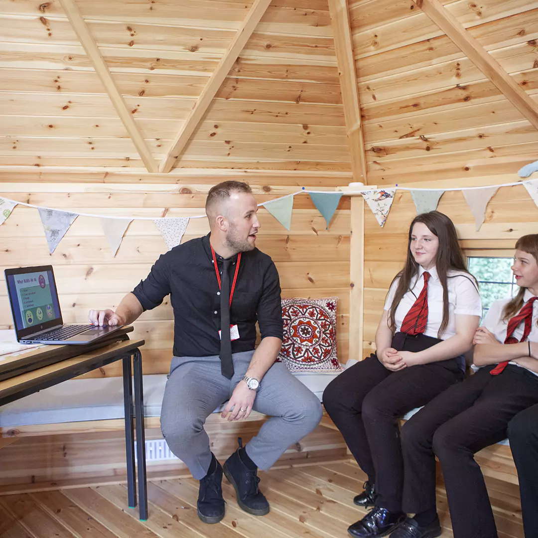 Teacher conducting lesson inside a timber school cabin decorated with bunting
