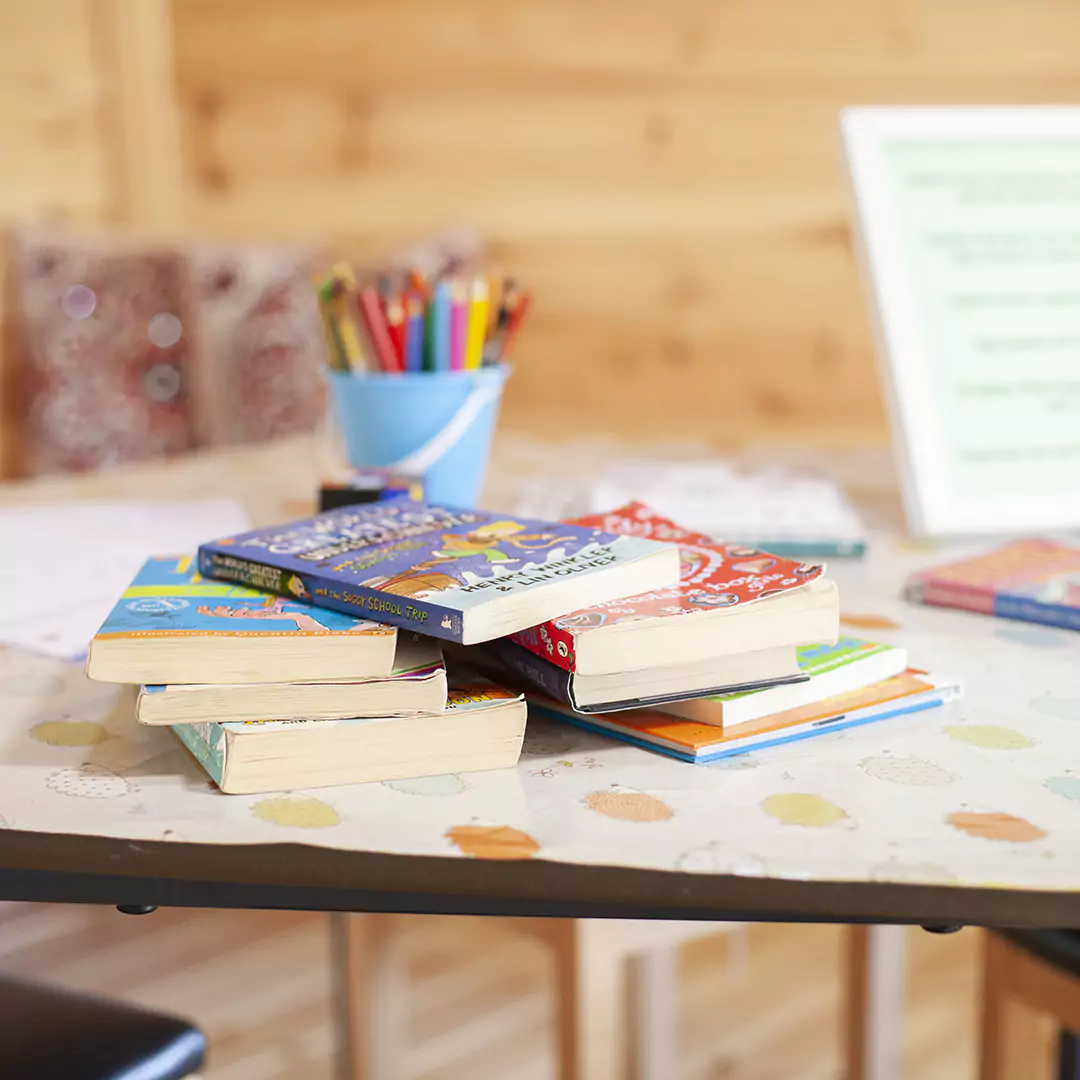 Interior close up shot on a table inside a scandi school cabin with books and pens on table