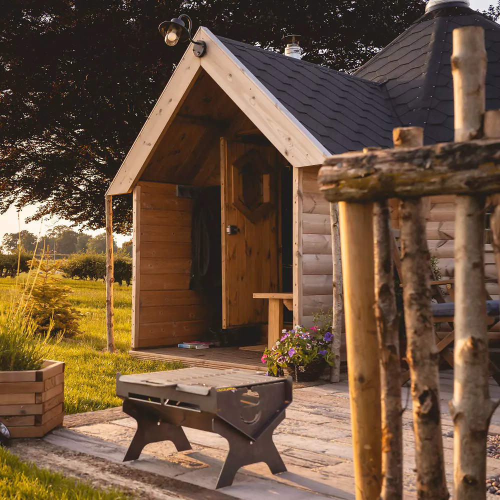Timber camping cabin for glamping with BBQ and planters outside
