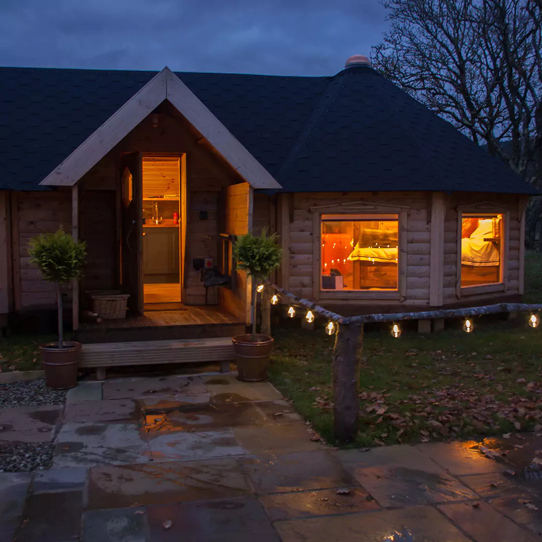 Entrance to connected timber camping cabins with miniature trees and porch