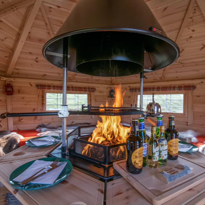 Interior of a BBQ hut set up for a dinner party with glasses, napkins and plates