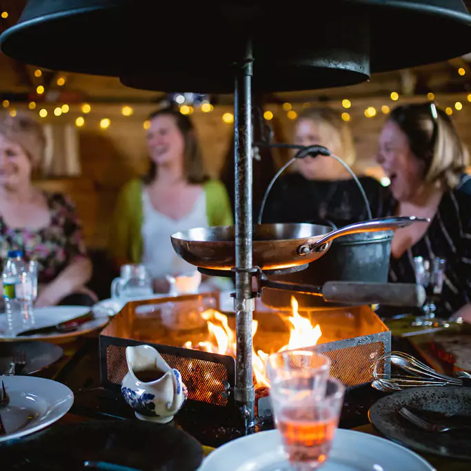 Interior of a BBQ camping hut with guests enjoying using the BBQ and drinks