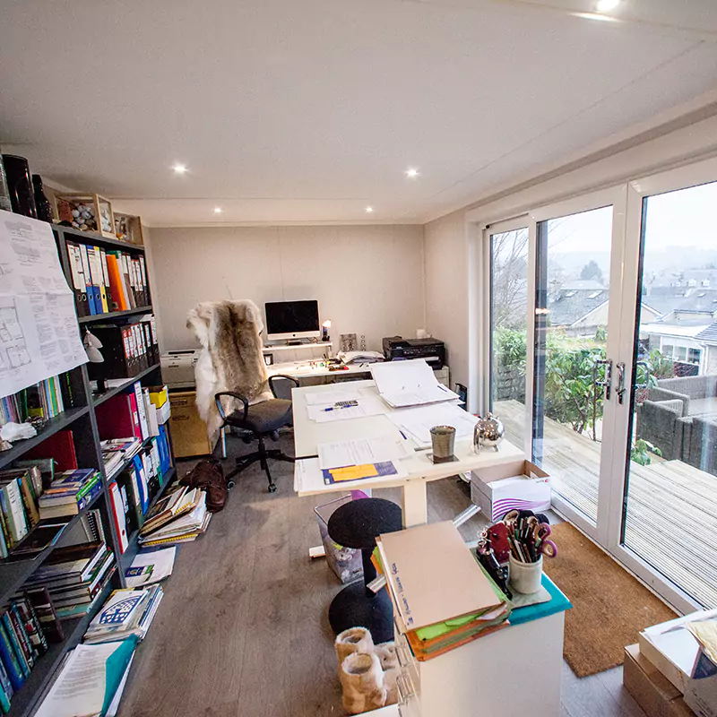 A desk inside a home business garden room with papers and a calculator on it