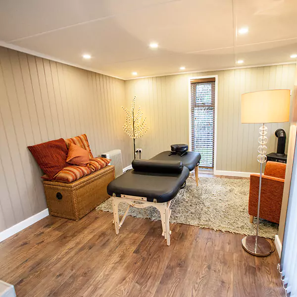inside view of redwood massage room with beige rug and orange cushions, home furnishings and sink