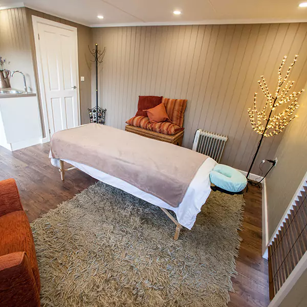 inside view of redwood massage room with beige rug and orange cushions, home furnishings and sink