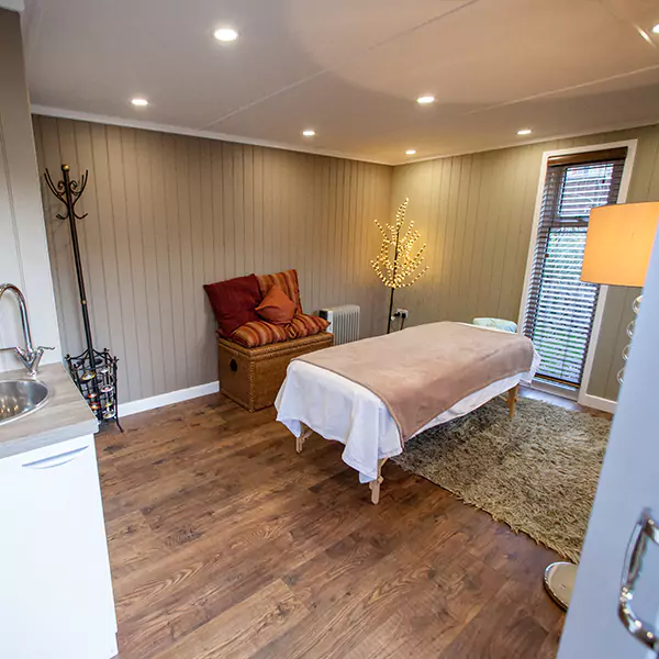 inside view of garden massage redwood room with partition door and in built sink unit