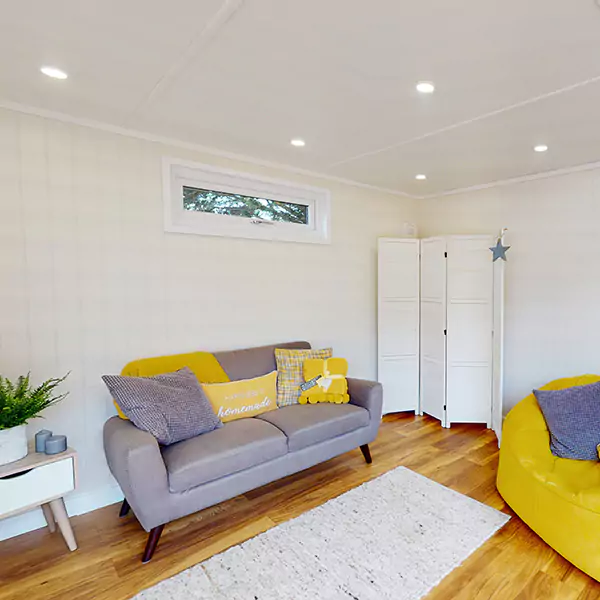 large grey and yellow sofas in garden veranda room with white rug