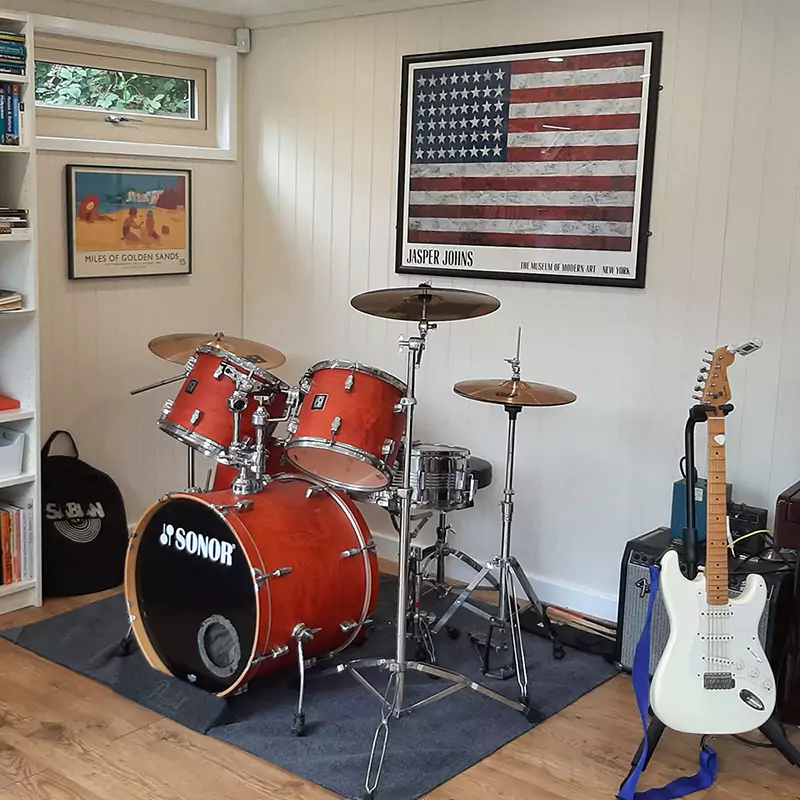Interior of garden music studio with drum kit & electric guitar