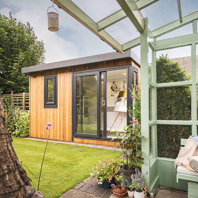 cedar garden room artist's studio with large green lawn area with trellises and plants