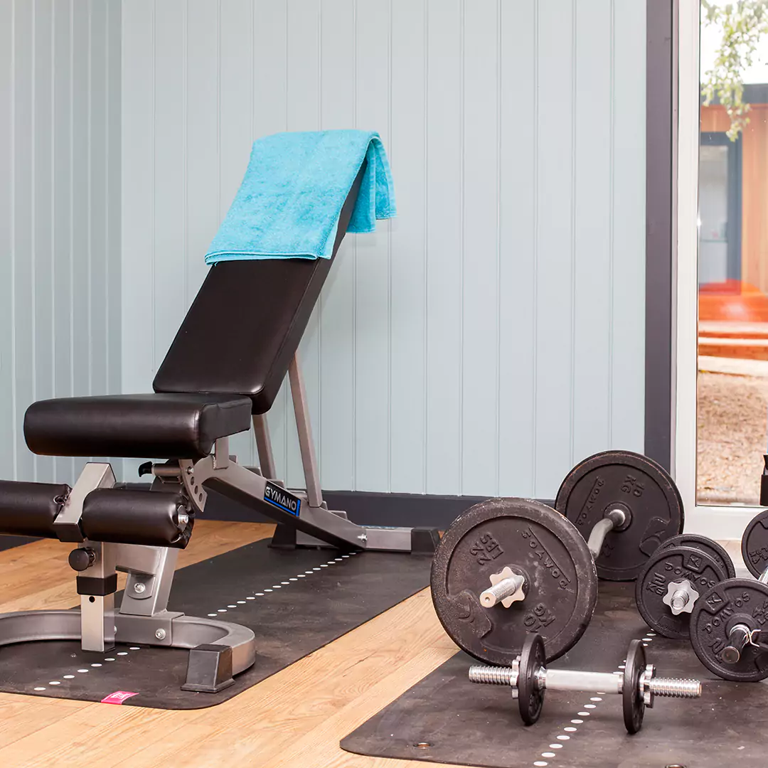 Internal shot of a garden gym room with bench & weights