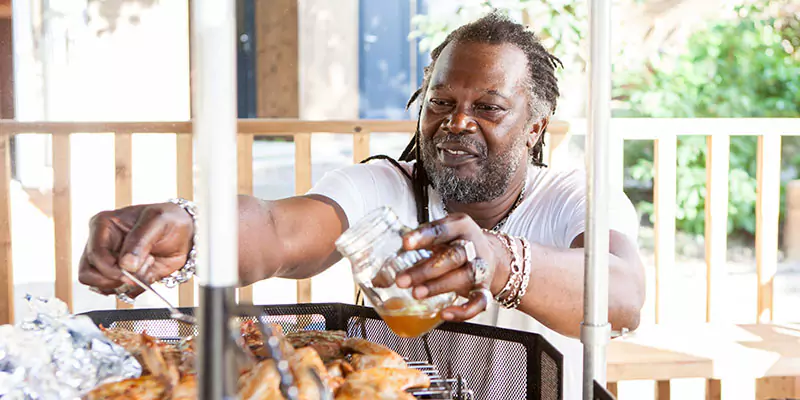 Levi Roots next to Arctic Cabins BBQ grill 