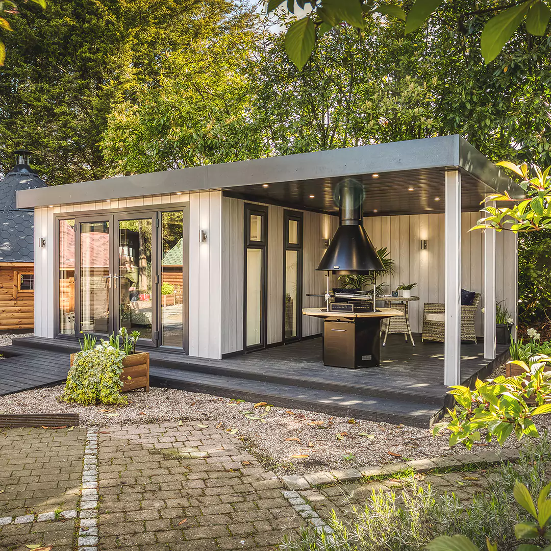 Show Site Grey Marley veranda room with BBQ Unit and composite decking with rattan furniture in background and potted plants in foreground