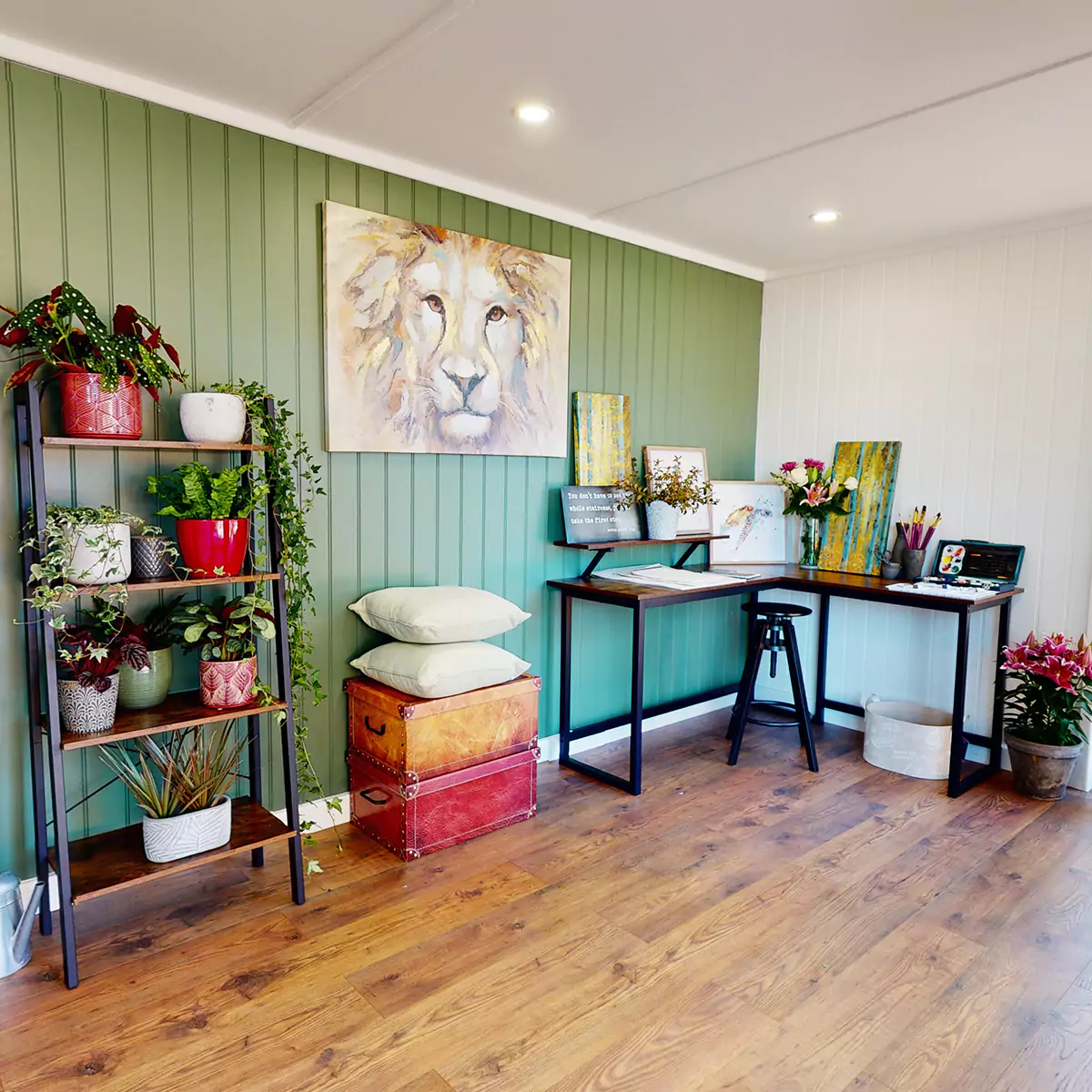 Interior of a garden artists studio looking across desk with easel and artists accessories