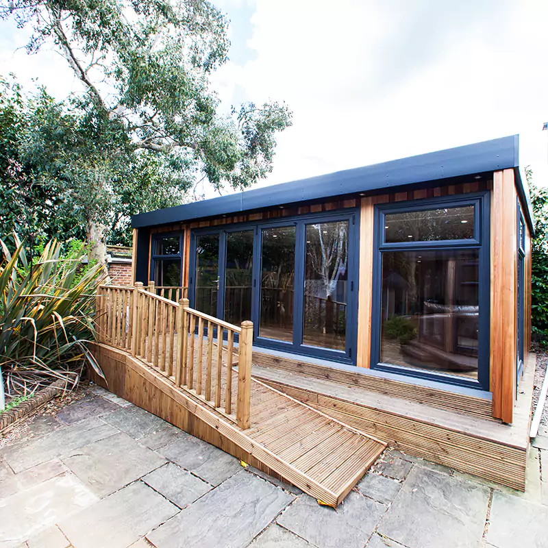 large cedar garden room with black fascia and timber ramp in front of it 