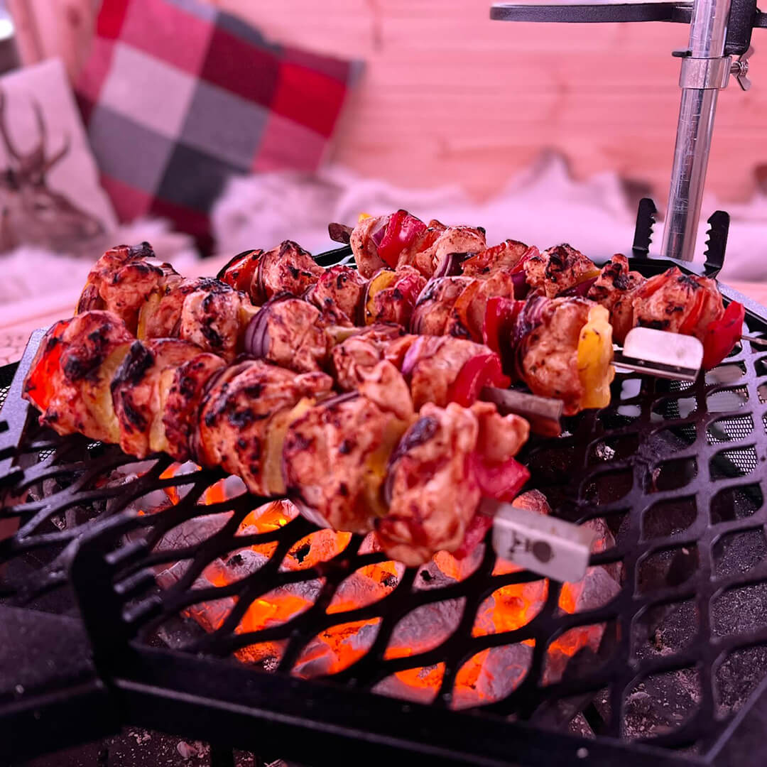 Close up of an Arctic Cabins bbq grill with skewers cooking over the hot coals