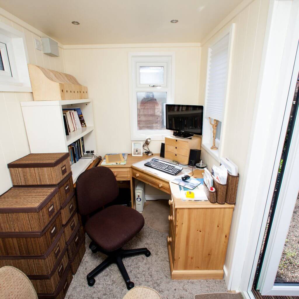 Internal view of micro office garden building with office furnishings and computer and desk and office files 