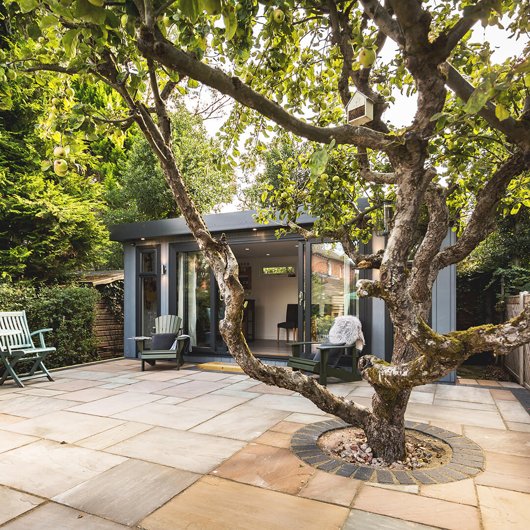 large garden bar building on a patio area with tree and chairs in it