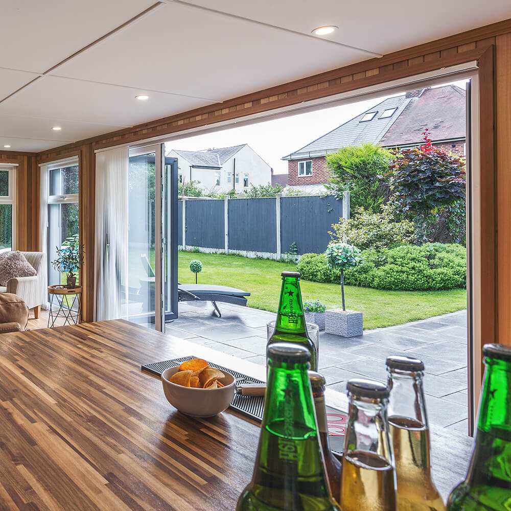 Marley Cabin Master Building with open Bi-Fold Doors internal view with beers and crisps on the bar and view of the lawn area