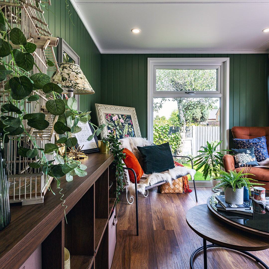 shoffice garden pod with a range of furniture and green walls with large glass window 