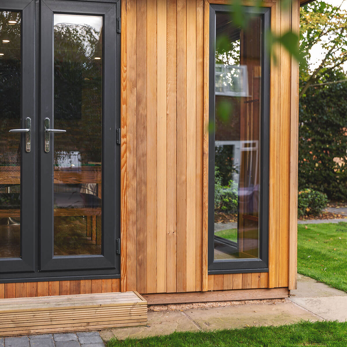 a large timber man cave garden building with black doors and windows 