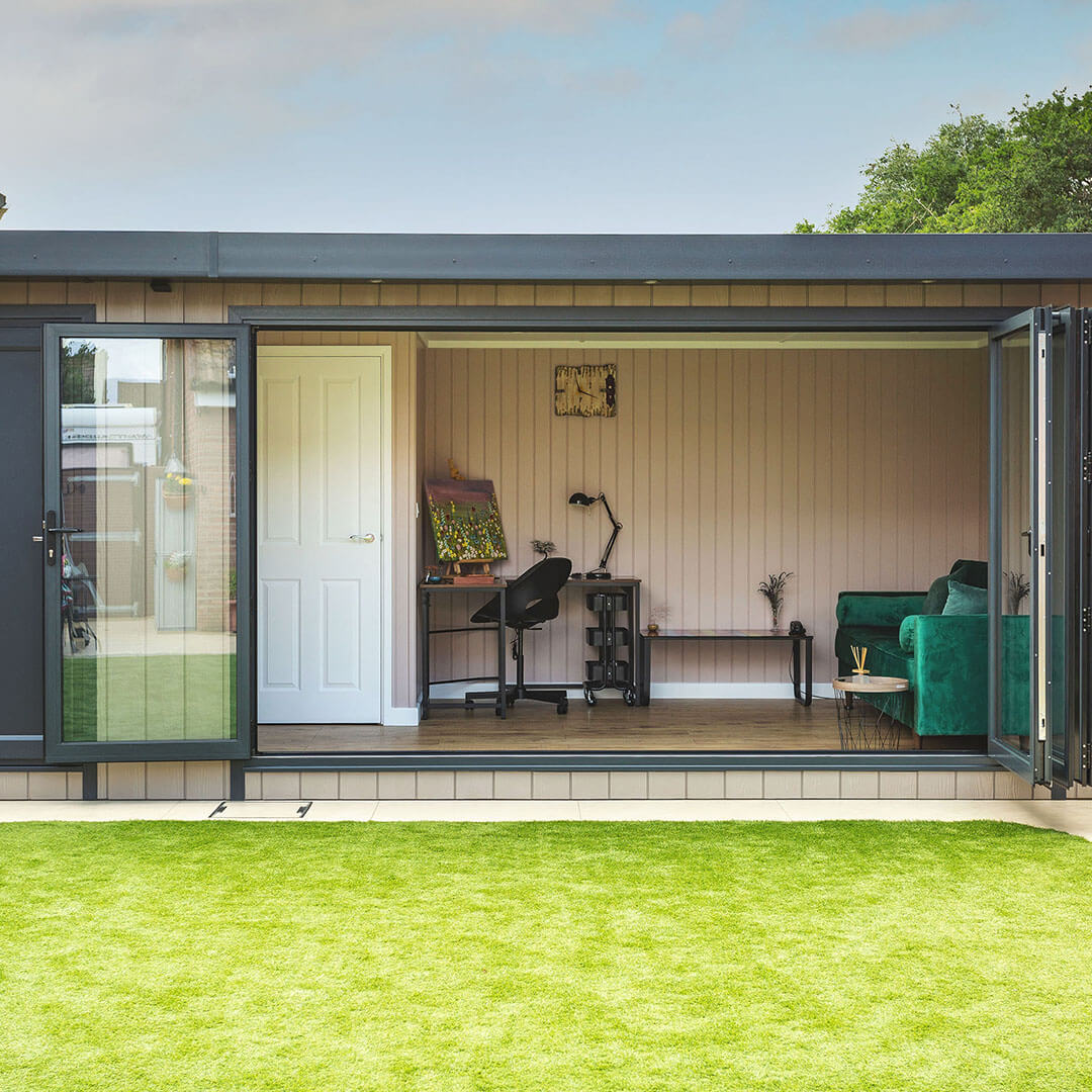 external view of garden room with open bi-fold doors and partition doors and large green velvet sofa and office furnishings