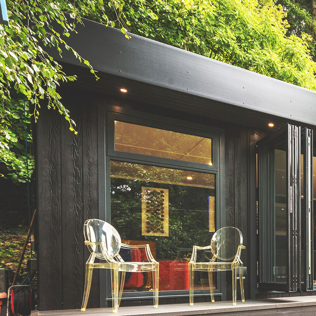  black marley board garden building with open bifold doors and garden furniture outside