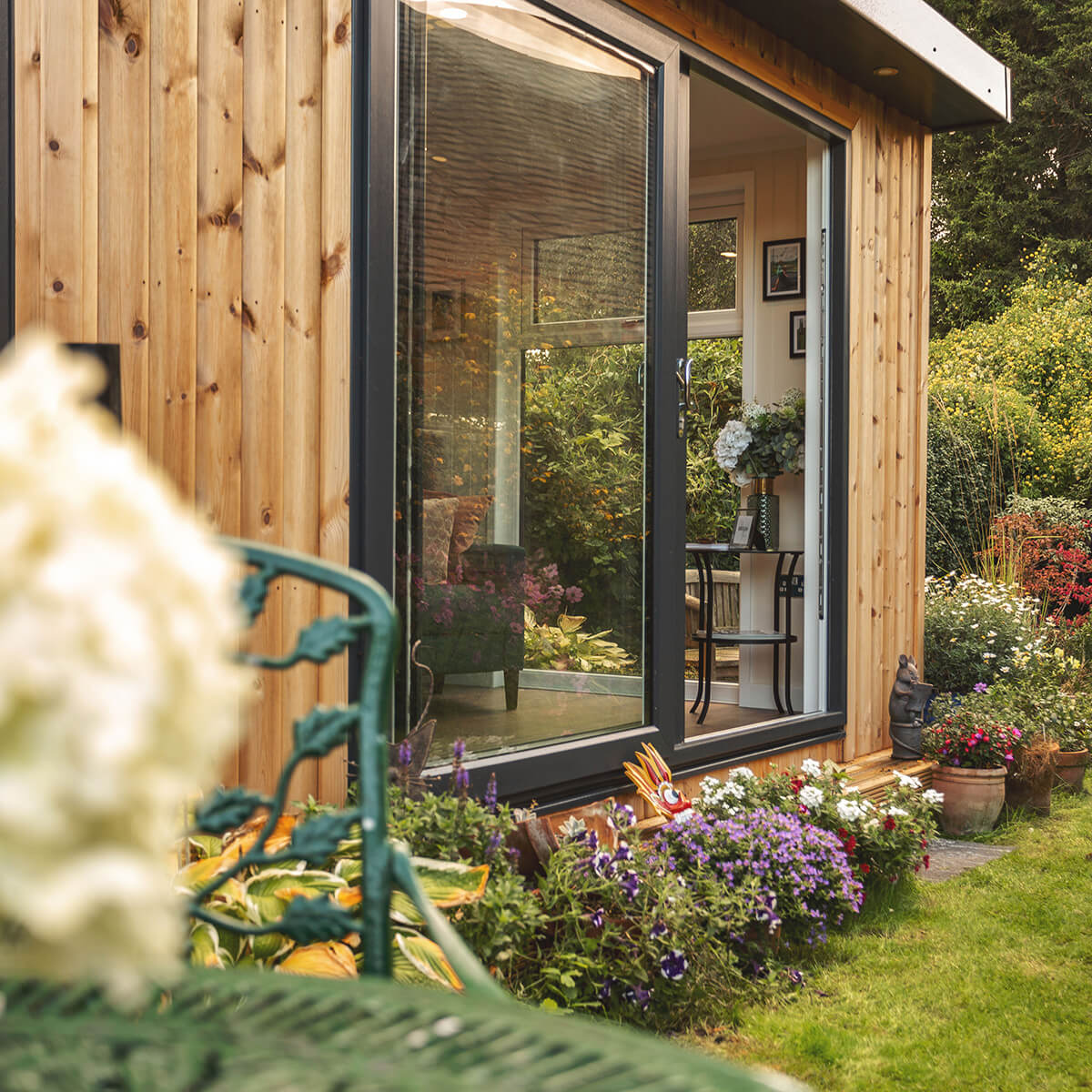 garden summerhouse building with sliding glass doors in outdoor area surrounded by potted plants