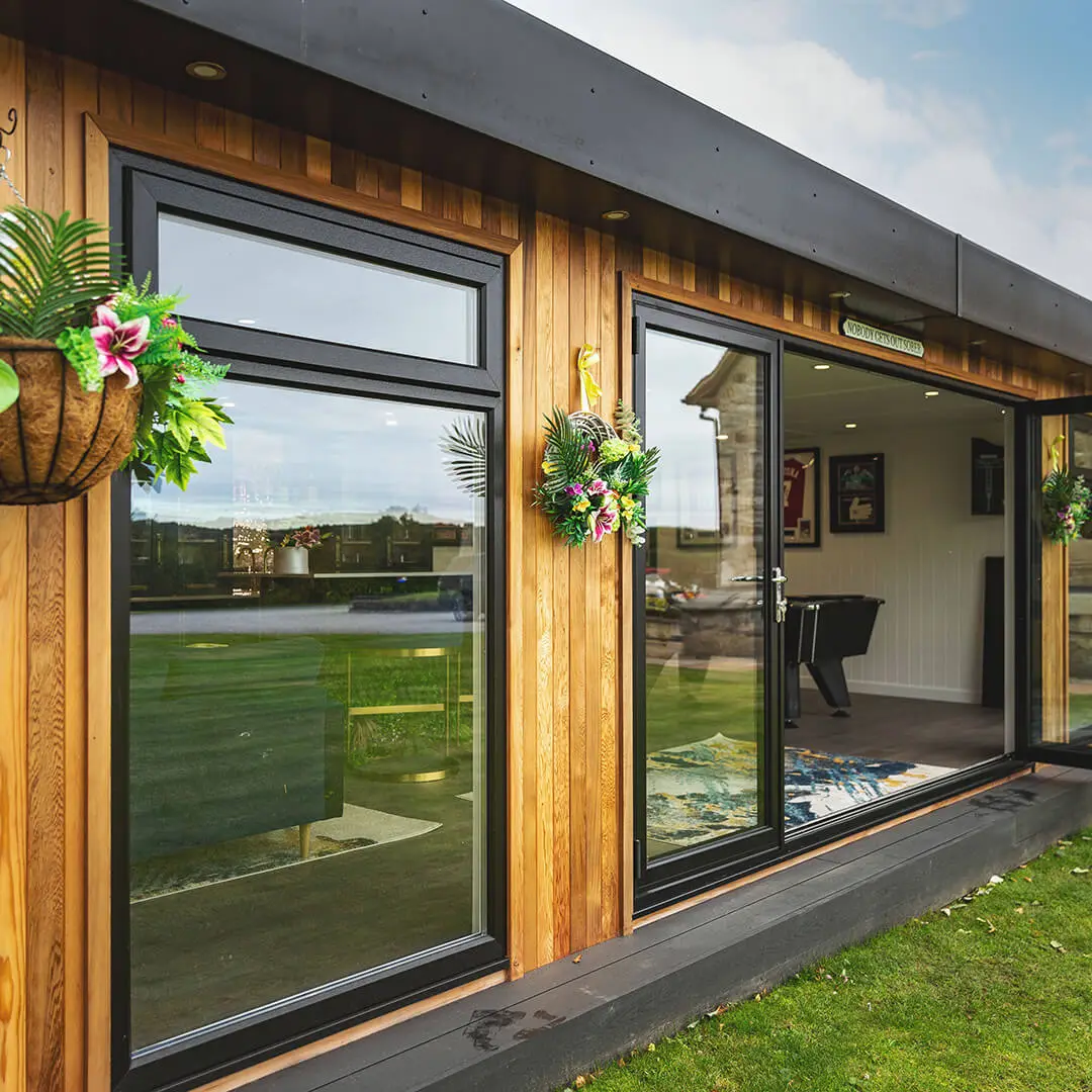 a cedar garden bar with glass windows and tropical hanging baskets