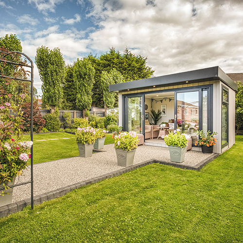 small grey garden summerhouse with decking and rattan furniture with sliding doors open