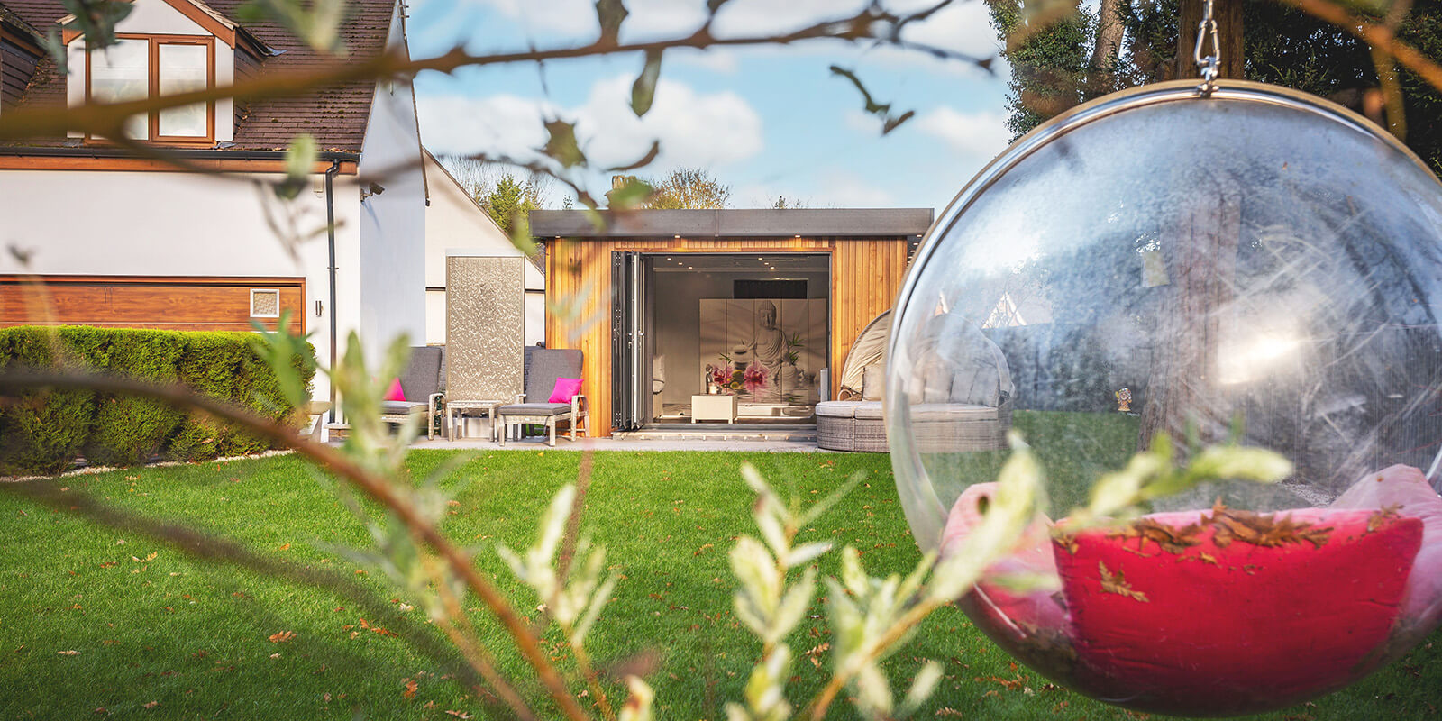 Impressive cedar garden room with open bifold doors seen in the distance through long garden