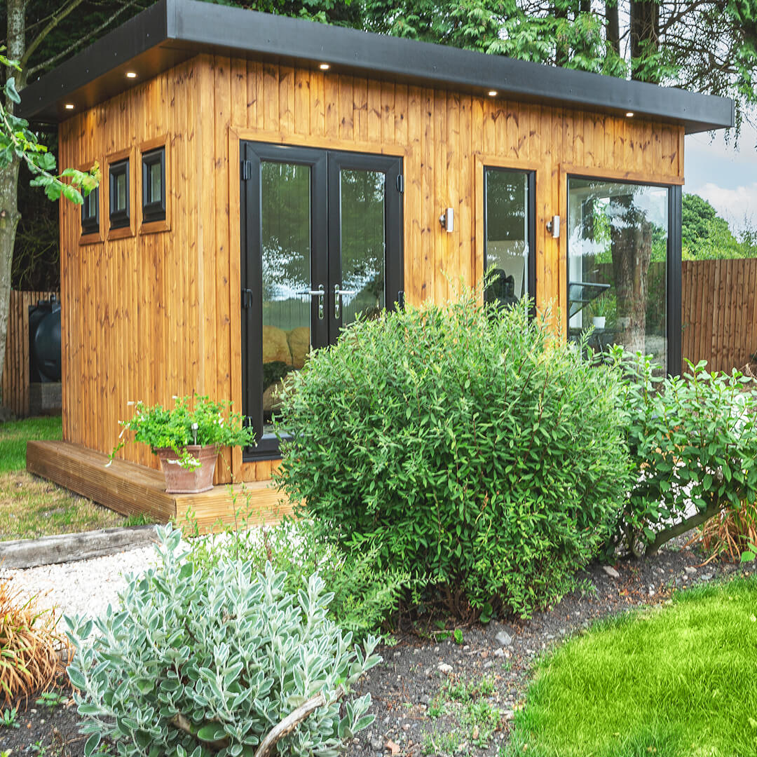 Redwood Garden Room Hobby And Craft Building in grassy lawn area with hedge in front