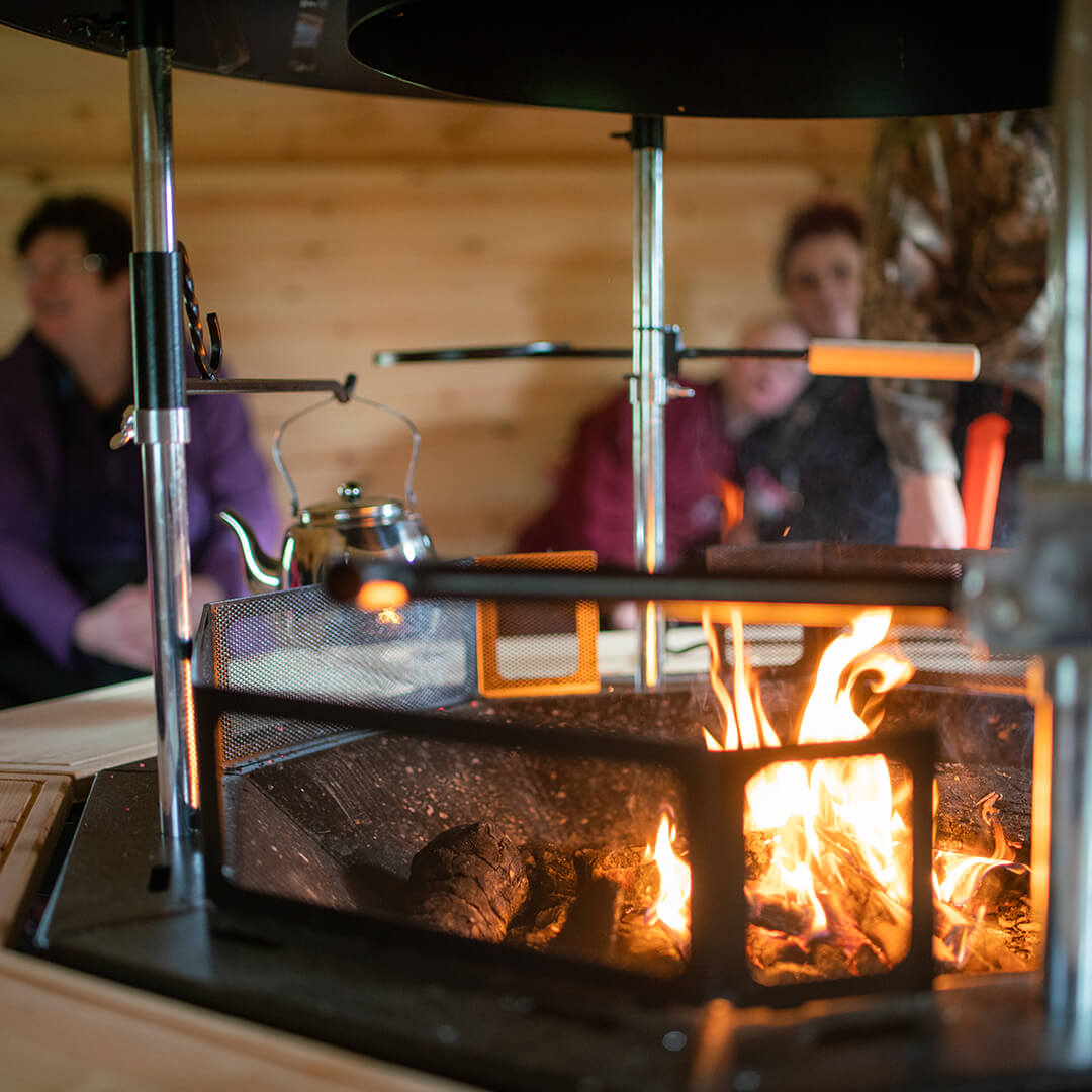 Inside a SEND school forest school timber cabin with pupils enjoying using the BBQ
