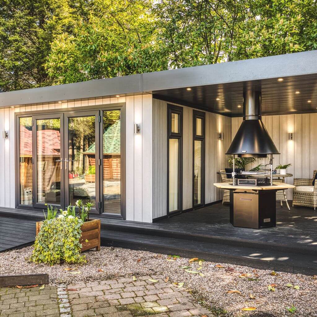 Show Site Grey Marley veranda room with BBQ Unit and composite decking with rattan furniture in background and potted plants in foreground