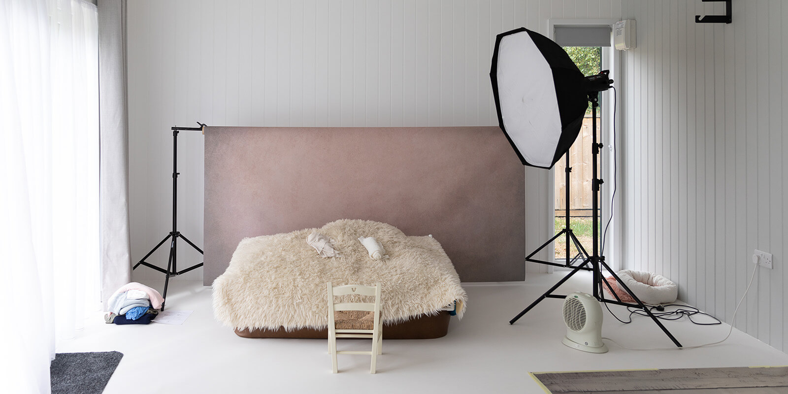 Interior of a garden photo studio with lighting equipment, backdrop and props