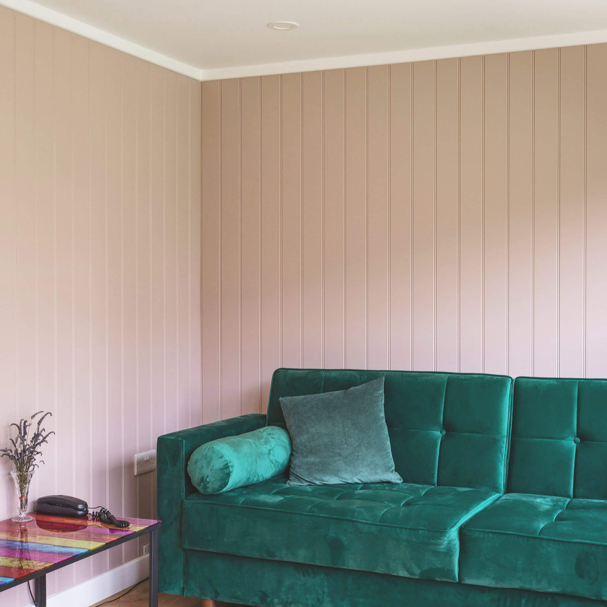 corner view of large green velvet sofa with colourful side table