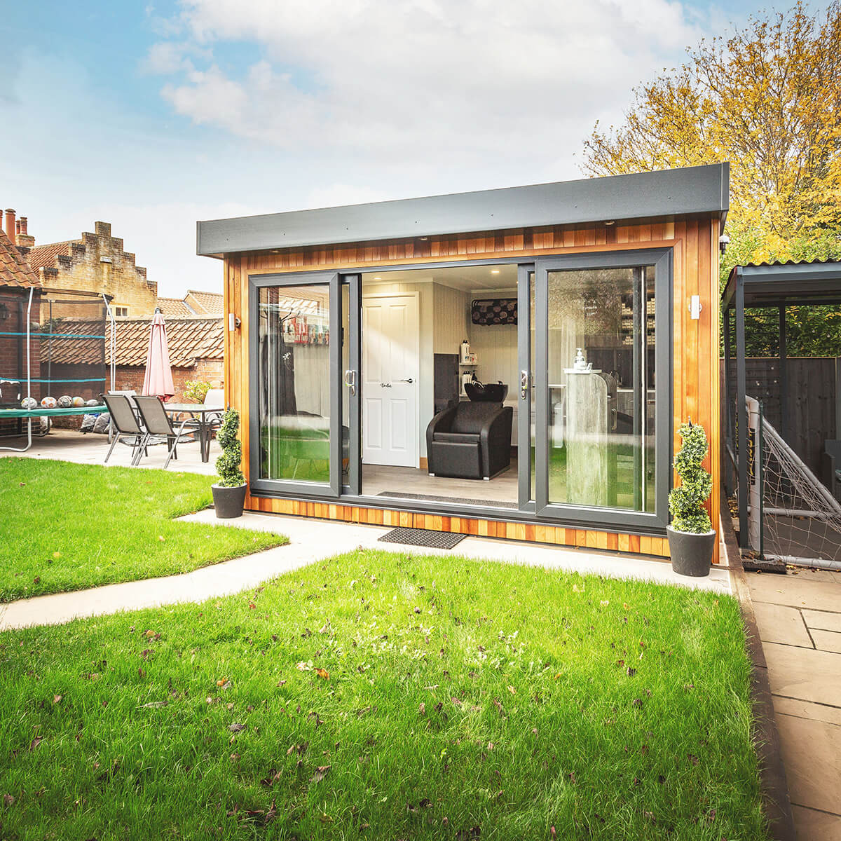 Cabin Master Garden Room Cedar with internal partition and door and black leather chair and patio area with potted plant 