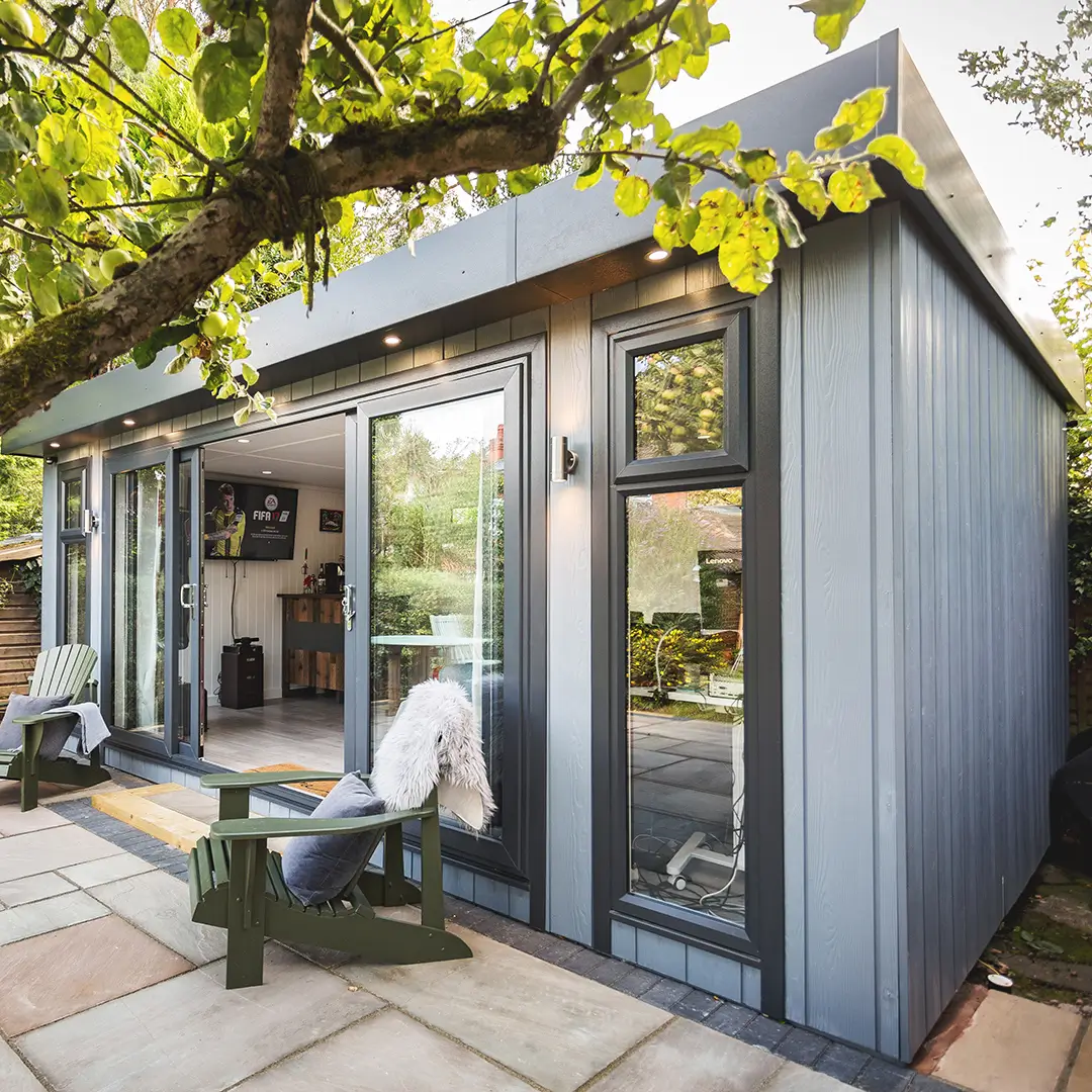 Marley Garden Room in patio area with green garden chairs and white throw and overhanging tree with green leaves