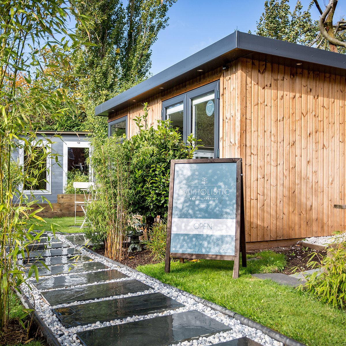 Redwood Beauty Room in garden with with business name on patio pathway and large A frame sign 