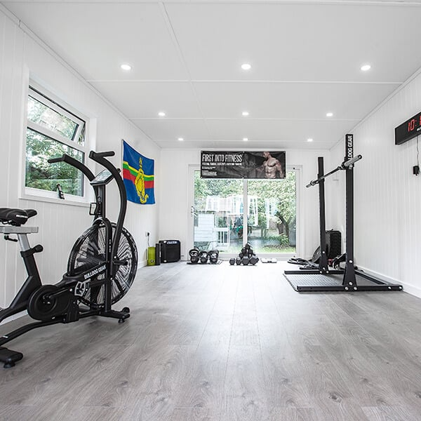 Inside Garden Gym with Squat Rack Bench Press and Large Mat Area with Dumbbells and Bike