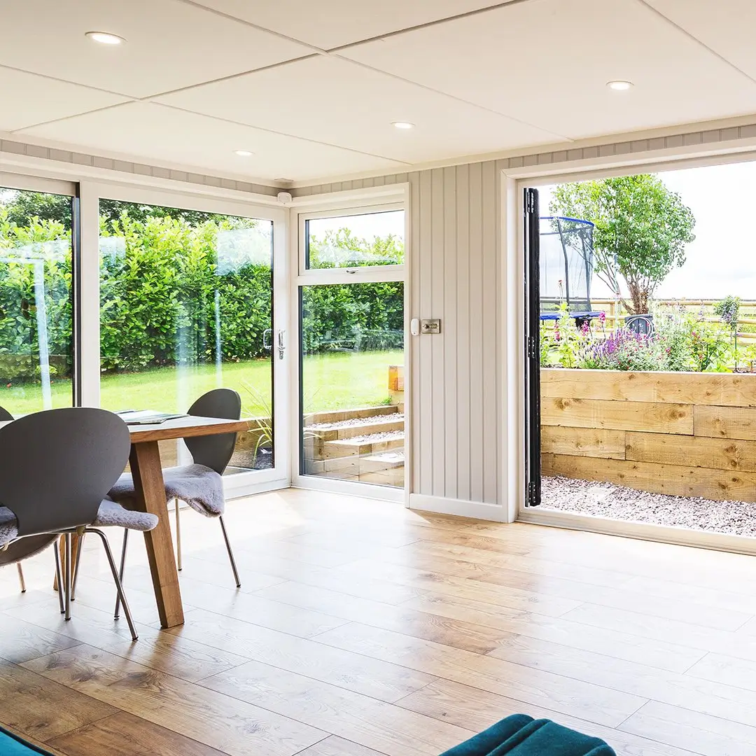 large garden room internal view with table and chairs and large sliding glass doors