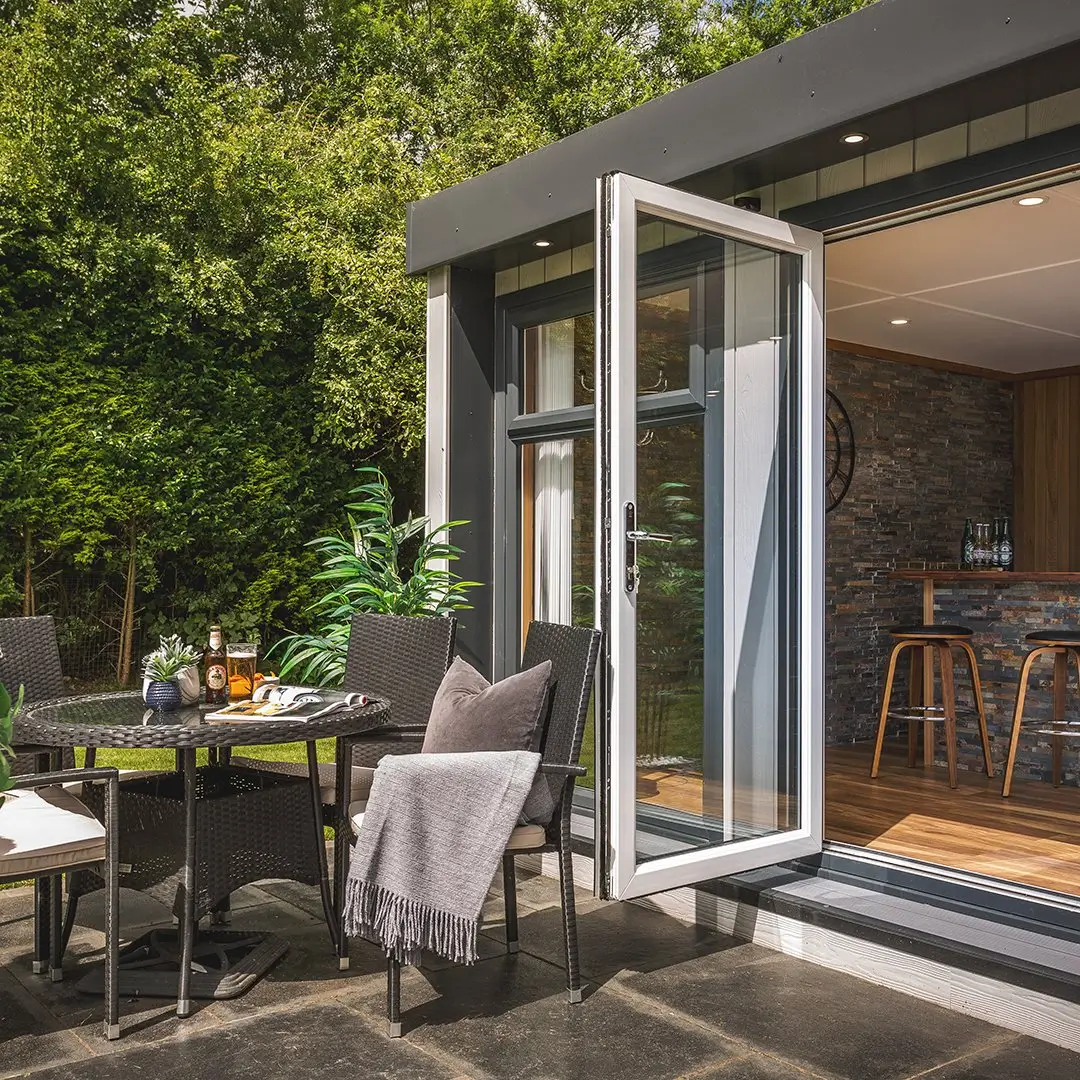 Cedar Garden Bar with bifold doors and view of slate grey feature wall with rattan garden furniture outside