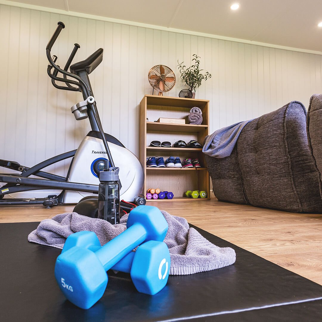 Inside a garden gym room with exercise bike, mats and weights