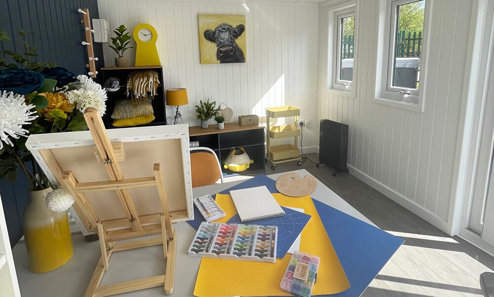 Interior of a garden room artists studio with navy and yellow accents, desk & artists eqipment