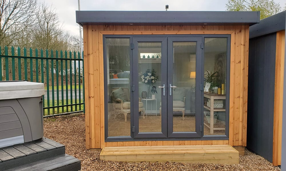 Small redwood garden room with black french doors