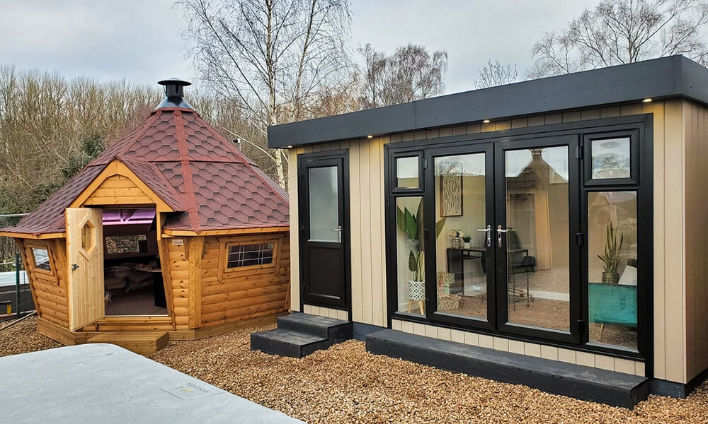 Shot at the Warwickshire Cabin Master show site showing a garden office with shed and a BBQ hut with red roof